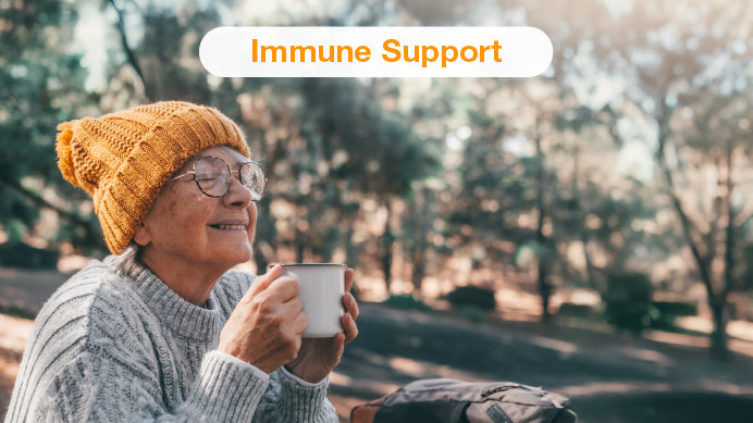 Woman drinking tea from a cup with a happy face and a text immune support 