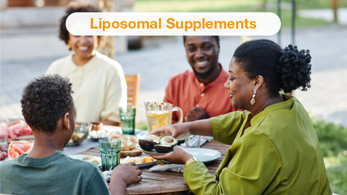 Happy people sitting at the table eating a meal with fresh vegetables and liposomal supplements